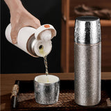 Person pouring liquid from a white container into a silver cup with a Titanium Thermal Brew Mug