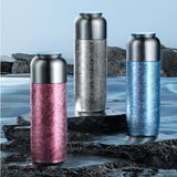 Three metallic thermos bottles with different color patterns on a natural background.