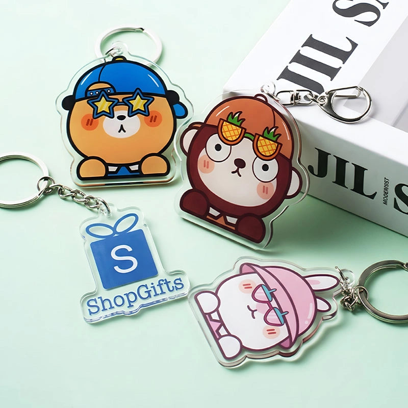 Four cartoon-themed keychains on a light green background