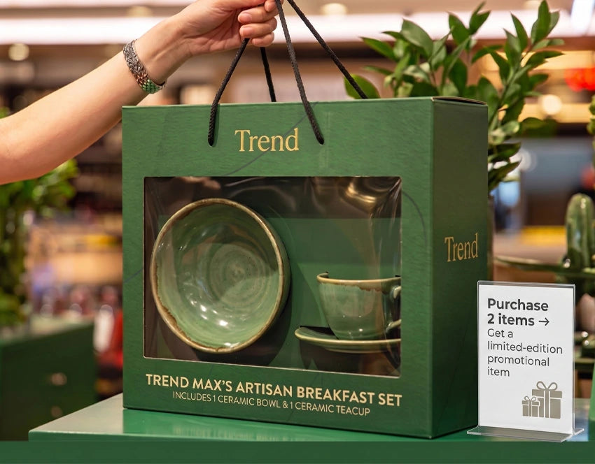 Green packaging box with 'Trend' branding containing a ceramic bowl and teacup set, held by a person.