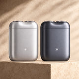 Xiaomi Pocket Electric Travel Shaver (S200) in grey with dual circular shaving foils on a wooden travel desk