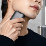 Xiaomi Pocket Electric Travel Shaver (S200) in grey with dual circular shaving foils on a wooden travel desk