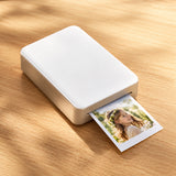 Xiaomi Portable Photo Printer Pro (KDRSHDY03HT) in white beside printed snapshots.