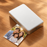 Xiaomi Portable Photo Printer Pro (KDRSHDY03HT) in white beside printed snapshots.