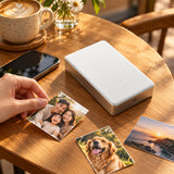 Xiaomi Portable Photo Printer Pro (KDRSHDY03HT) in white beside printed snapshots.
