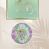 Decorative mirror with floral and bird design on a textured surface